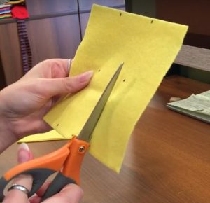 Cutting yellow felt into 1 inch strips for hat