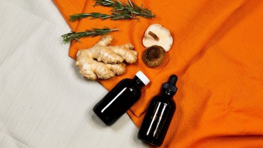 Image of 2 NHV amber glass bottles with rosemary sprig, piece of ginger and shiitake mushroom