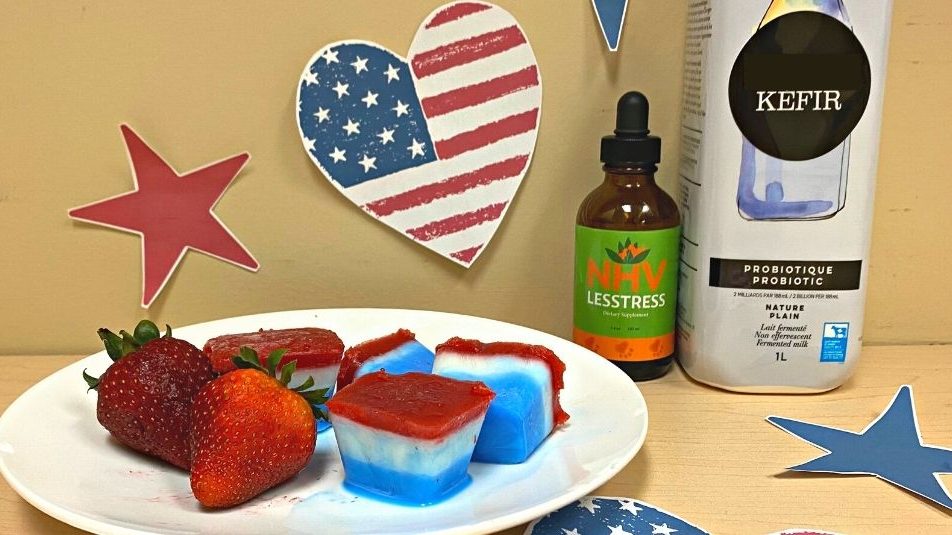 Pawtriot Pops! 4th of July treats for dogs on a plate next to strawberries, a bottle of NHV Lesstress, and a bottle of kefir
