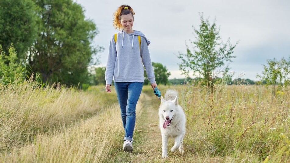 A woman walking her dog in nature.