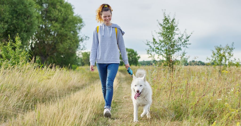 A woman walking her dog in nature.